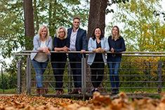 Die fünf Mitarbeiter von Spree Immobilien stehen an einem Geländer