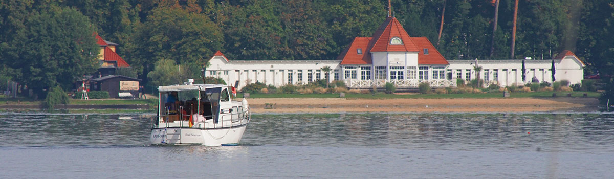 Ein Boot fährt auf dem Scharmützelsee in Richtung Ufer,dort liegt das Seebad Bad Saarow.